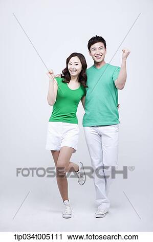 Stock Image - a man and a woman in green t-shirt posing cheering gesture. Fotosearch