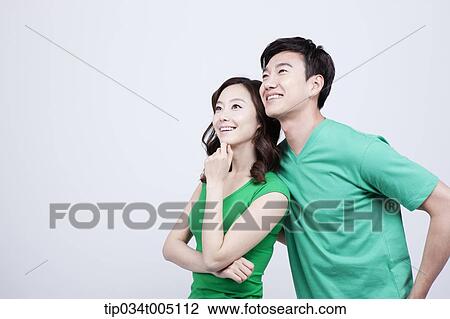Stock Image - a man and a woman in green t-shirt looking at same place. Fotosearch