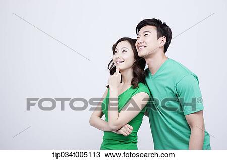 Stock Image - a man and a woman in green t-shirt looking at same place. Fotosearch