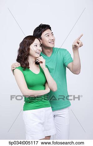 Stock Photo - a man and a woman in green t-shirt smiling while looking at same place. Fotosearch