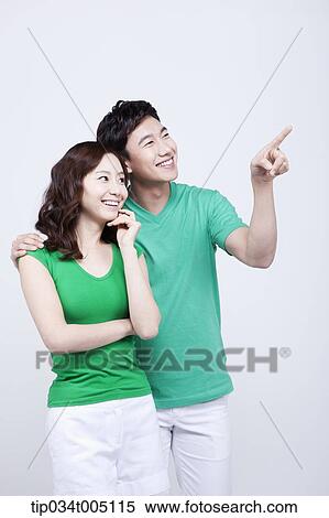 Stock Photography - a man and a woman in green t-shirt smiling while looking at same place. Fotosearch