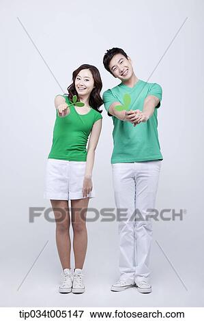 Stock Photo - a man and a woman in green t-shirts holding big sprouts. Fotosearch