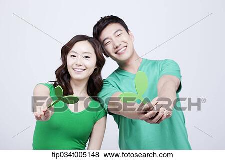 Stock Photo - a man and a woman in green t-shirts holding big sprouts. Fotosearch
