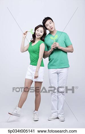 Stock Image - a man and a woman posing while holding sprouts. Fotosearch