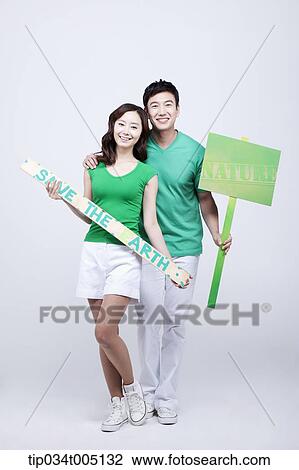 Stock Image - a man and a woman posing with signboards saying environmentally friendly phrases. Fotosearch