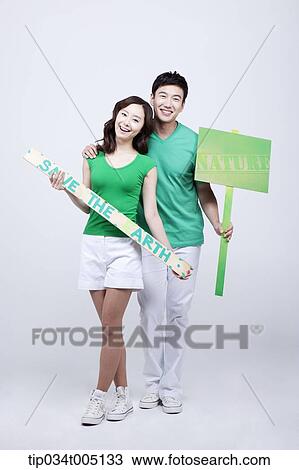 Stock Image - a man and a woman posing with signboards saying environmentally friendly phrases. Fotosearch