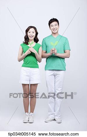Stock Photography - a man and a woman standing still holding sprouts with two hands . Fotosearch