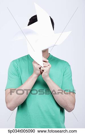 Stock Image - a man in green t-shirt covering his face with a pinwheel. Fotosearch