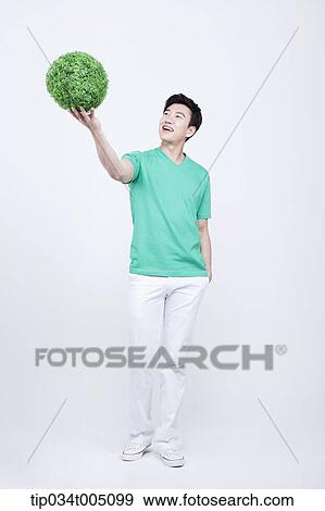 a man in green t-shirt holding a ball made from grass View Large Photo Image Stock Photo - a man in green t-shirt holding a ball made from grass. Fotosearch