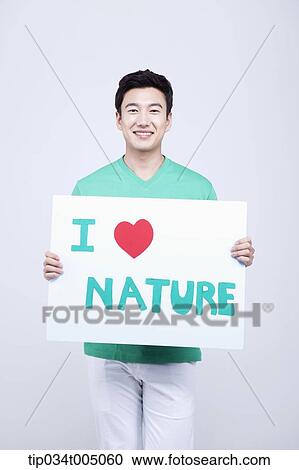 Stock Image - a man in green t-shirt holding a picket with I love nature sign . Fotosearch