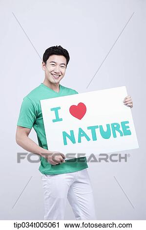 Stock Image - a man in green t-shirt holding a picket with I love nature sign . Fotosearch