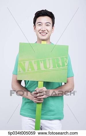 Stock Photo - a man in green t-shirt holding a picket with nature sign . Fotosearch