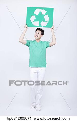 Stock Image - a man in green t-shirt holding a signboard with recycling logo. Fotosearch