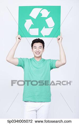 Stock Image - a man in green t-shirt holding a signboard with recycling logo. Fotosearch