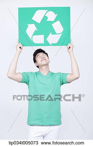 Stock Image - a man in green t-shirt holding a signboard with recycling logo. Fotosearch