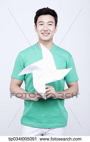 Stock Image - a man in green t-shirt holding a pinwheel. Fotosearch