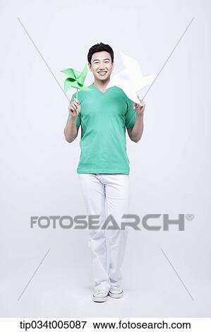 Stock Photo - a man in green t-shirt holding two pinwheels. Fotosearch