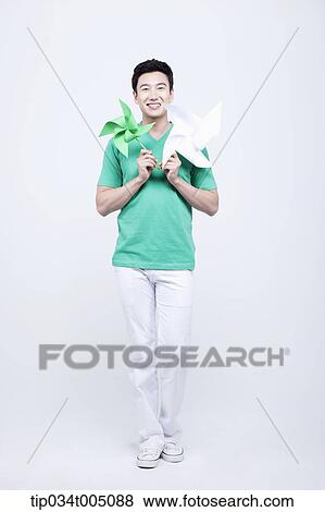 Stock Photo - a man in green t-shirt holding two pinwheels. Fotosearch