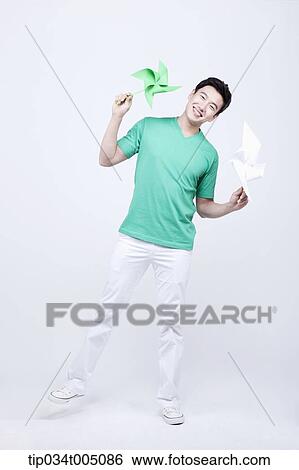 Stock Photograph - a man in green t-shirt posing with two pinwheels. Fotosearch