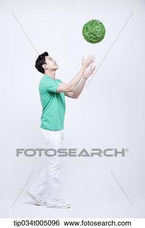 a man in green t-shirt tossing a ball made from grass View Large Photo Image Stock Photograph - a man in green t-shirt tossing a ball made from grass . Fotosearch