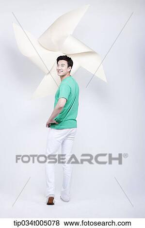 Stock Photo - a man in green t-shirt turning back with a giant pinwheel in his hand. Fotosearch