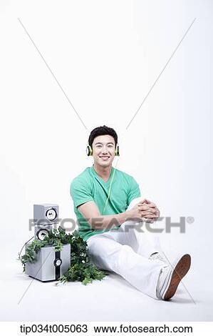 Stock Image - a man listening to a music with an audio set with plants . Fotosearch
