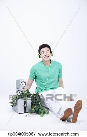 Stock Photo - a man listening to a music with an audio set with plants . Fotosearch