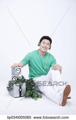 Stock Photography - a man listening to a music with an audio set with plants . Fotosearch
