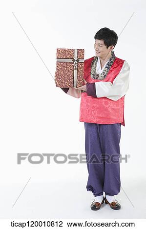 Stock Image - a man wearing a Hanbok holding a present . Fotosearch