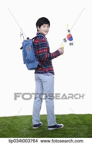 Picture - a man with a backpack looking behind holding a Korean flag. Fotosearch