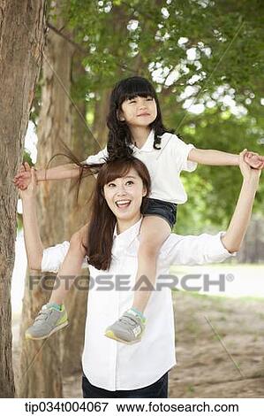 Stock Photo - a mother and a daughter on mother's shoulders posing together. Fotosearch