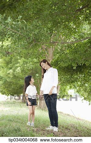 a mother and a daughter standing in front of a tree View Large Photo Image Stock Photo - a mother and a daughter standing in front of a tree. Fotosearch
