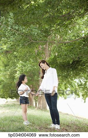 Stock Photo - a mother and a daughter standing in front of a tree. Fotosearch