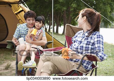 Stock Image - a mother drinking a coffee while daughter sits on father's lap . Fotosearch