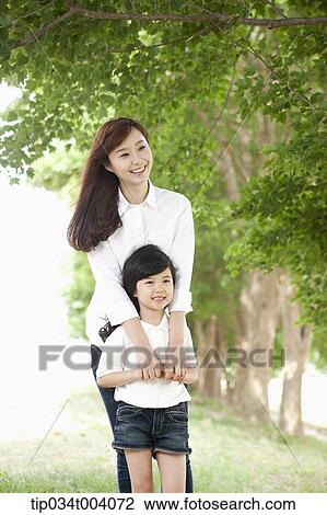 Stock Image - a mother standing behind her son . Fotosearch