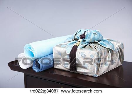 Stock Photo - a package in Korean traditional wrap and Korean traditional paper rolls on a table. Fotosearch