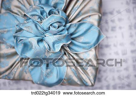Stock Photo - a package wrapped in a traditional wrap with nice big ribbon . Fotosearch