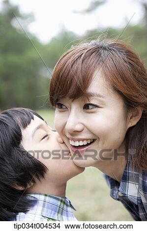 Picture - a son kissing on mother's cheek. Fotosearch