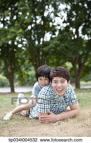Stock Image - a son lying on dad's back . Fotosearch