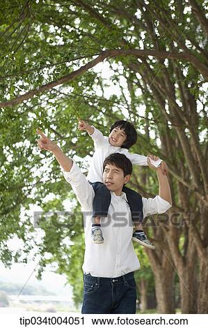 Stock Image - a son sitting on father's shoulders posing . Fotosearch