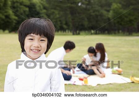 a son smiling with a background of family enjoying a picnic View Large Photo Image Stock Image - a son smiling with a background of family enjoying a picnic . Fotosearch