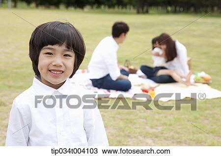 a son smiling with a background of family enjoying a picnic View Large Photo Image Stock Image - a son smiling with a background of family enjoying a picnic . Fotosearch