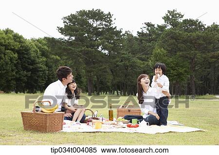 Stock Photography - a son stood up in a picnic blanket while family having a picnic. Fotosearch