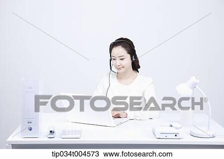 Stock Image - a telemarketer sitting at office desk. Fotosearch