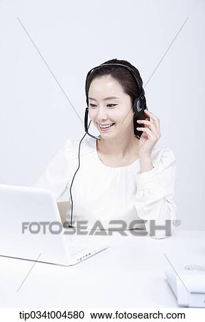 Stock Image - a telemarketer smiling while working . Fotosearch