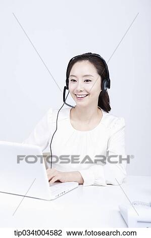 Stock Image - a telemarketer smiling while working . Fotosearch