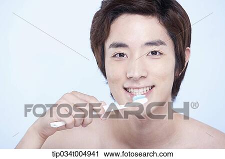 Stock Image - a topless man brushing his teeth. Fotosearch