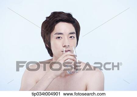 Stock Image - a topless man drinking a glass of water. Fotosearch