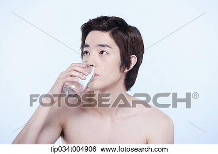 Stock Photograph - a topless man drinking a glass of water. Fotosearch