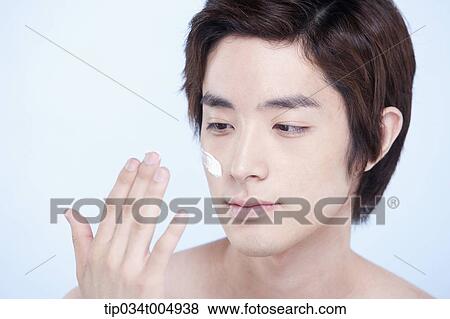 Stock Photo - a topless man looking at his fingers after putting on lotion. Fotosearch